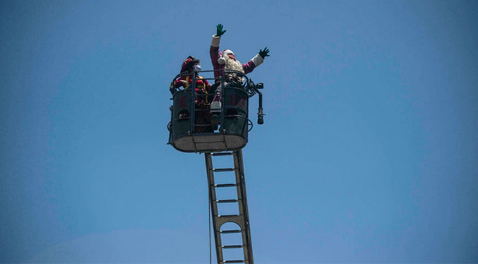 En escalera de bomberos Papá Noel entrega regalos a niños con COVID-19 en Perú