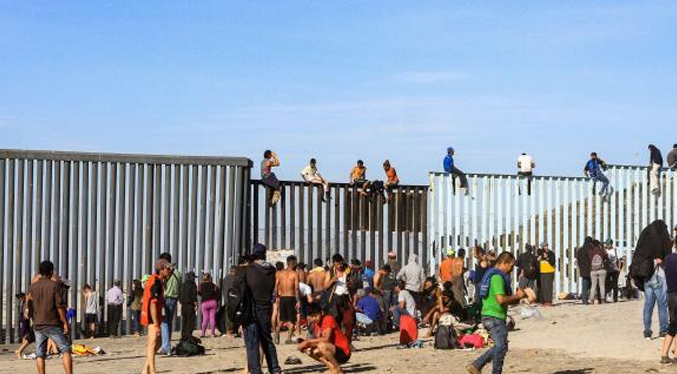 Migrantes esperan en el muro fronterizo para tratar de alcanzar el Sueño Americano